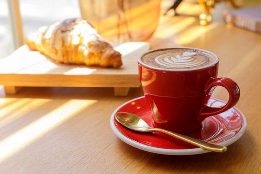 Close up hot cappuccino, latte, caramel macchiato on table with blur coffee shop background. Hot cappuccino coffee on wood table with blur croissant background. breakfast at coffee shop. softfocus select coffee