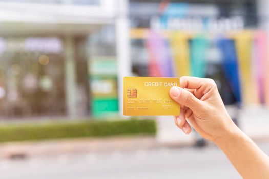 Women hand holding gold credit card member card over blur department store background. Business, shopping, lifestyle concept. With copy space