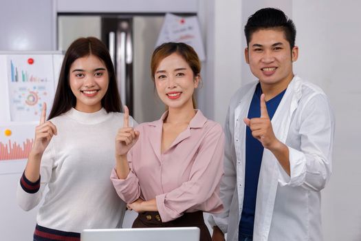 Business Team brainstorm meeting. Group of business people working at Private Home Office.Young business people show index finger .Asian teamwork business people successful celebrate