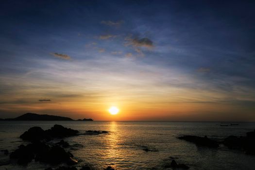 Beautiful sunset over the clam sea with cloud sky background. Sunset over tropical beach. Nature summer  concept. Peak sunset over sea with yellow light reflect on sea water. Tranquil seascape. Horizon over the water.