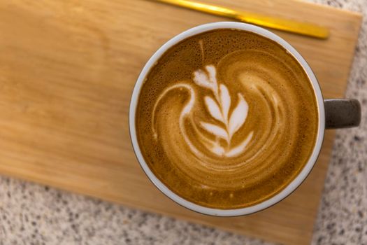 Soft focus Top view close up of hot espresso, latte coffee in a red ceramic cup on blur wood table background.