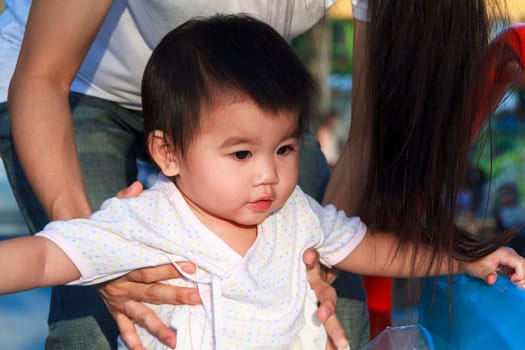 Hands of mother holding daughter at playground outdoor. Happy baby girl play at park with mother hands holding. Mother help her daughter for play slide at playground.