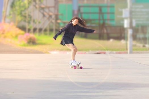 Asian women on skates board outdoors on beautiful summer day. Happy young women play surfskate at park on morning time. Sport activity lifestyle concept