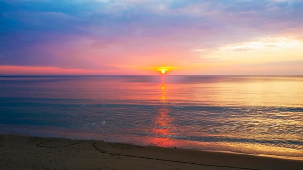 Beautiful sunset over the clam sea with cloud sky background. Sunset over tropical beach. Nature summer  concept. Peak sunset over sea with yellow light reflect on sea water. Tranquil seascape. Horizon over the water.