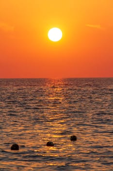 Beautiful sunset over the clam sea with cloud sky background. Sunset over tropical beach. Nature summer  concept. Peak sunset over sea with yellow light reflect on sea water. Tranquil seascape. Horizon over the water.