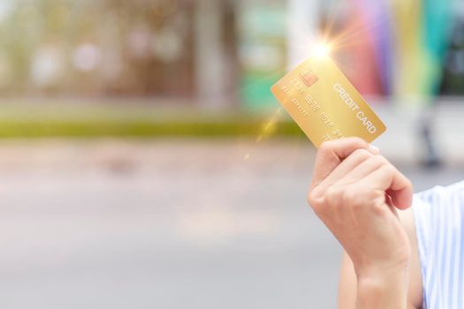 Women hand holding gold credit card member card over blur department store background. Business, shopping, lifestyle concept. With copy space