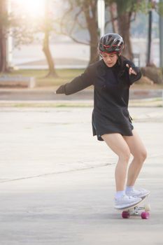 Asian women on skates board outdoors on beautiful summer day. Happy young women play surfskate at park on morning time. Sport activity lifestyle concept