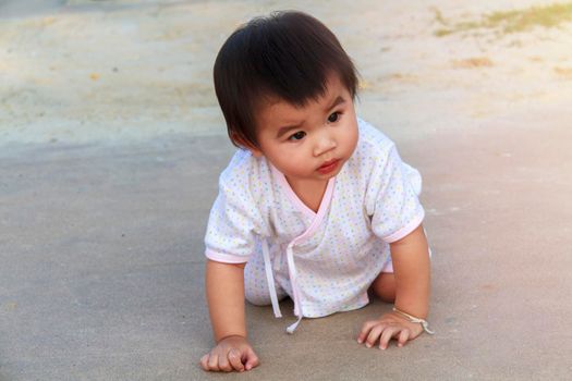 Small baby, little girl creeping, playing on road and sant at beach. Cute baby try to creeping and play on outdoor park. Little girl happy to creeping play at park.