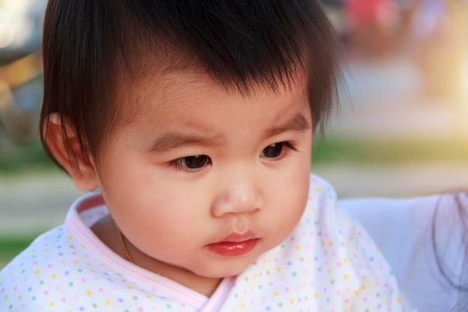 Close up portrait little girl. Cute adorable asian little girl play in park with sun ray background. Happy baby girl play in outdoor park. Close up and soft focus baby gril.