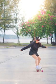 Asian women on skates board outdoors on beautiful summer day. Happy young women play surfskate at park on morning time. Sport activity lifestyle concept