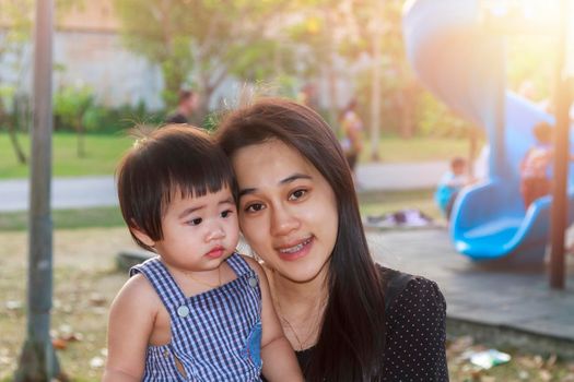 Portrait of happy Asian mother and daughter. Asian woman and little toddler girl in the playground park. Happy family playing together at playground park