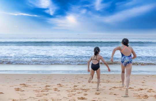 Stop motion happy two children wear swimwear running from beach to the sea. Happy family holiday summer concept. Two girl running to beach with copy space