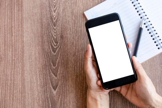 Top view female hands holding smart phone with blank white screen. Women hands workspace, close-up hand holding smartphone blank screen for text and content on wood table background.