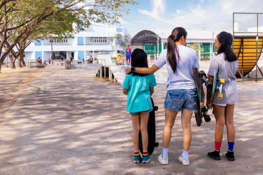 Two little girl hand hold skateboard, surf skate on public skate ramp park background. Free relax skateboard surf skate trendy concept. Fashion portrait of female hands holding surf skateboard