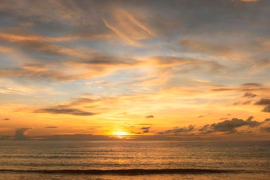 Beautiful sunset over the clam sea with cloud and sky background. Sunset over tropical beach. Nature summer  concept. Peak sunset over sea with yellow light reflect in cloud.