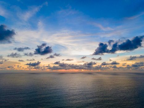 Beautiful sunset over the clam sea with cloud and sky background. Sunset over tropical beach. Nature summer  concept. Peak sunset over sea with yellow light reflect in cloud.