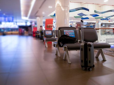 Backpack and travel bag on chair in international airport. Public chair at airport have sign Social distancing protection Coronavirus disease (Covid-19) infection . New normal, travel bubble and social distancing concepts,