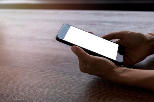 Top view female hands holding smart phone with blank white screen. Women hands workspace, close-up hand holding smartphone blank screen for text and content on wood table background.