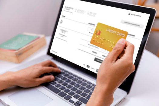 Woman holding credit card and using laptop computer. Women working at home. Online shopping, e-commerce, internet banking, spending money, working from home concept. Technology shopping online concept