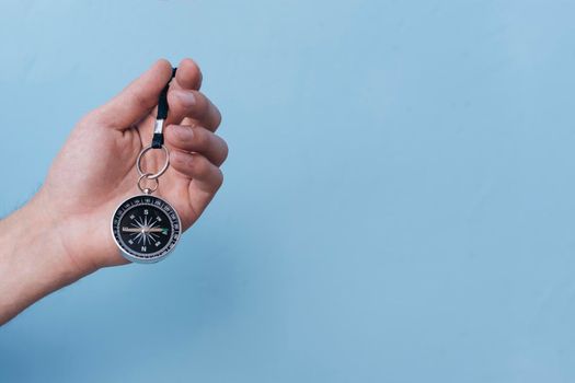 close up human hand holding navigational compass blue backdrop