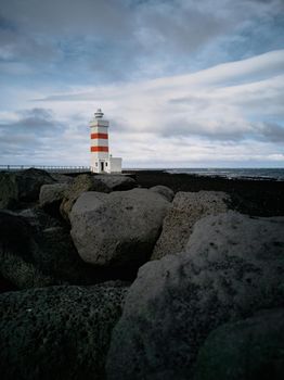 Lighthouse with red stripes wide angle over the black volcanic rocks