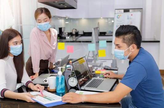 Asian small business start up multiracial working at Private Home Office social distancing among Coronavirus outbreak. Business people show and talking about document chart financial report. 