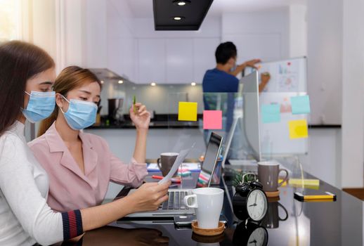 Asian Business Team Meeting Brainstorming Business start up working at Private Home Office social distancing among Coronavirus outbreak New generation business people meeting analysis work from laptop