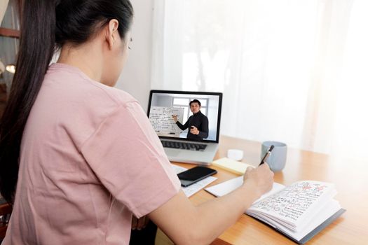 rear angle view of video conference with teacher on laptop at home. Student using laptop online learning with teacher. Covid-19 , coronavirus  e-learning education concept.