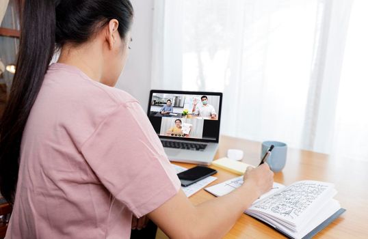Rear view Businessman and businesswoman analysis financial chart with videoconference online meeting. Hand of businesswomen using laptop meeting with diverse colleagues. Covid-19 working from home. 