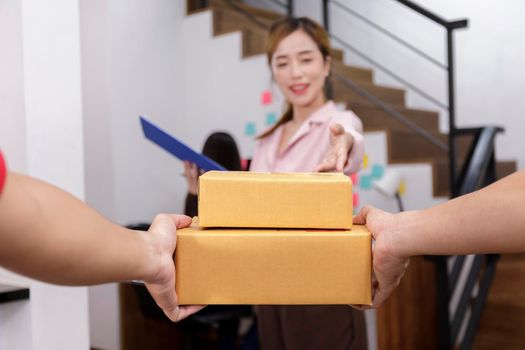 Hand of delivery man delivering package to homeowner. Woman accepting a delivery of boxes from deliveryman. Hand of Delivery man sent box package to women. soft focus selective box Delivery concept.
