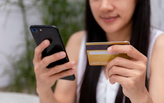 Young woman holding credit card and using laptop computer. Women working at home. Online shopping, e-commerce, internet banking, spending money, working from home concept. Technology shopping online concept.
