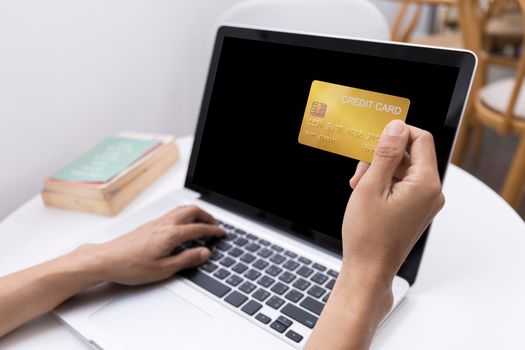 Young woman holding credit card and using laptop computer. Women working at home. Online shopping, e-commerce, internet banking, spending money, working from home concept. Technology shopping online concept.