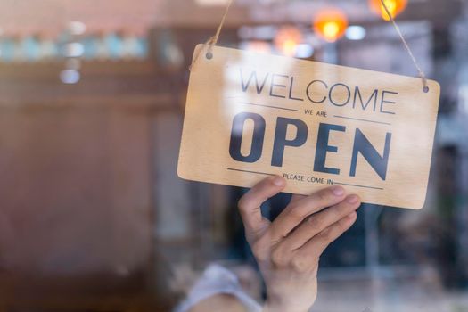 Hand of asian owner retail ,coffee shop woman turning sign board to open. Protection to pandemic of coronavirus. Open store,restaurant or pub due to lockdown quarantine of covid-19.