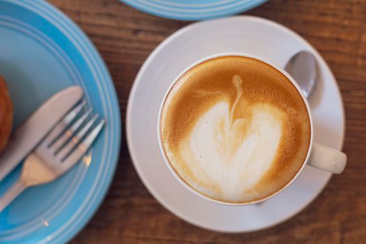 Top view Close up hot cappuccino, latte on table with blur coffee shop background. Hot cappuccino coffee on wood table with blur brakefast background. breakfast at coffee shop. soft focus select coffee