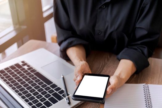 Female hands holding smart phone with blank white screen. Women hands workspace, close-up hand holding smartphone blank screen for text and content at cafe coffee shop