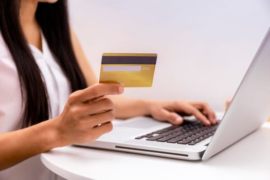 Young woman holding credit card and using laptop computer. Women working at home. Online shopping, e-commerce, internet banking, spending money, working from home concept. Technology shopping online concept.