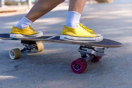 Close-up Asian women surf skate or skateboard outdoors on beautiful morning. Happy young women play surf skate at ramp park on morning time. Close up Asian women leg wear sneaker play surf skate on public park. Sport concept
