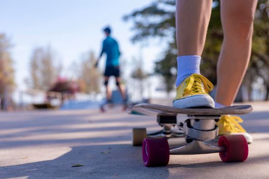 Close-up Asian women surf skate or skateboard outdoors on beautiful morning. Happy young women play surf skate at ramp park on morning time. Close up Asian women leg wear sneaker play surf skate on public park. Sport concept