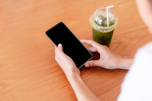 Close up hands of woman using mobile phone, cell phone in coffee shop. Hands of women holding blank empty screen smart phone in cafe. Women relax with mobile phone sit in restaurant