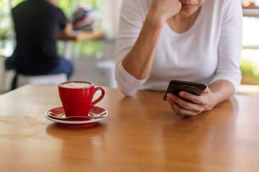 Close up hands of beautiful young woman holding mobile, smart phone sitting in cafe. Soft focus hands of women holding and use cell phone in coffee shop. Tectechnology and lifestyle concept.