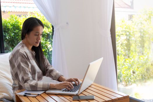 Asian woman working with laptop. Business woman busy working on laptop computer at home. Asian woman freelance online working with laptop. Business and lifestyle concept