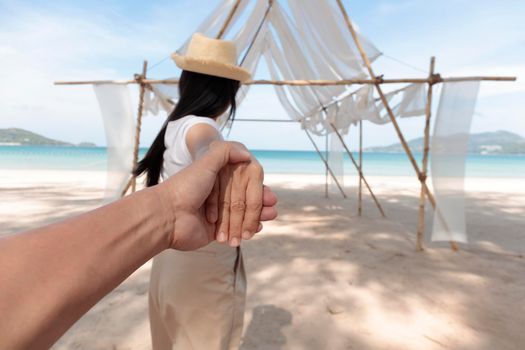 POV Point of view Follow me woman leads boyfriend by hand to the sea,. Close up hands and blur Back view of happy girl walking on beach. Couple holiday travel on beach. Summer vacation.