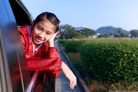 Asian little girl looking something out the car. In the morning, the girl was looking at something outside the car window on the way to school. children relax with street view from the car. Family at car concept.