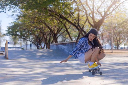Young asian women play surf skate board at park skate ramp outdoors on morning. Happy women play surfskate board at park . Sport activity lifestyle concept