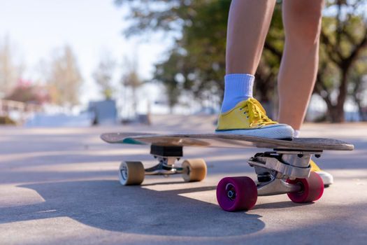 Close-up Asian women surf skate or skateboard outdoors on beautiful morning. Happy young women play surf skate at ramp park on morning time. Close up Asian women leg wear sneaker play surf skate on public park. Sport concept