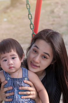 Portrait of happy Asian mother and daughter. Asian woman and little toddler girl in the playground park. Happy family playing together at playground park