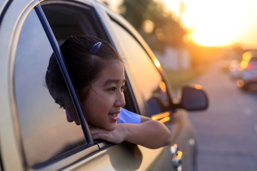 Asian little girl looking something out the car. In the morning, the girl was looking at something outside the car window on the way to school. children relax with street view from the car. Family at car concept.