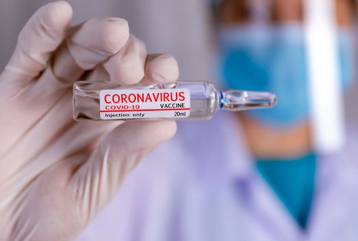 Covid-19 coronavirus vaccine. Close up hands of scientist show Covid-19 vaccine in glass vial. Hands of doctor wear latex glove holding Covid-19 vaccine in glass vial. Healthcare and medical concept.