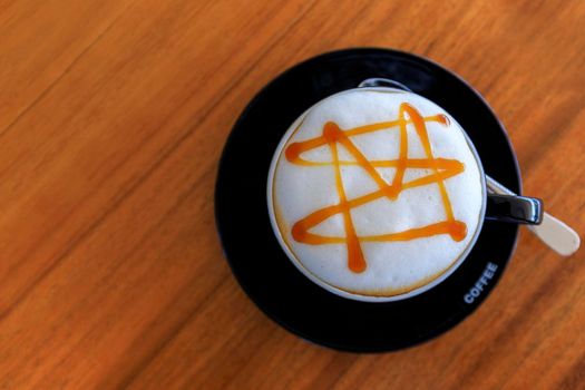 Top view close up of hot espresso coffee in a white ceramic cup on a wood table background. 
