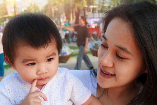 Portrait of happy Asian mother and daughter. Asian woman and little toddler girl in the playground park. Happy family playing together at playground park